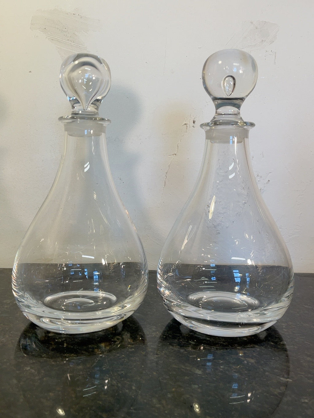 Pair of clear glass vintage spirit decanters with different decorative stoppers on the original marble surface