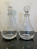 Pair of clear glass vintage spirit decanters with different decorative stoppers on the original marble surface