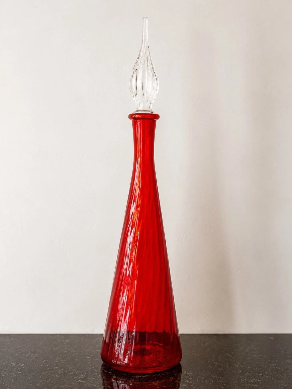 Full view of the ruby red optic glass bottle with clear glass stopper