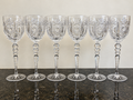 Enhanced full-set photograph of six tall hand-cut crystal hock goblets on dark stone