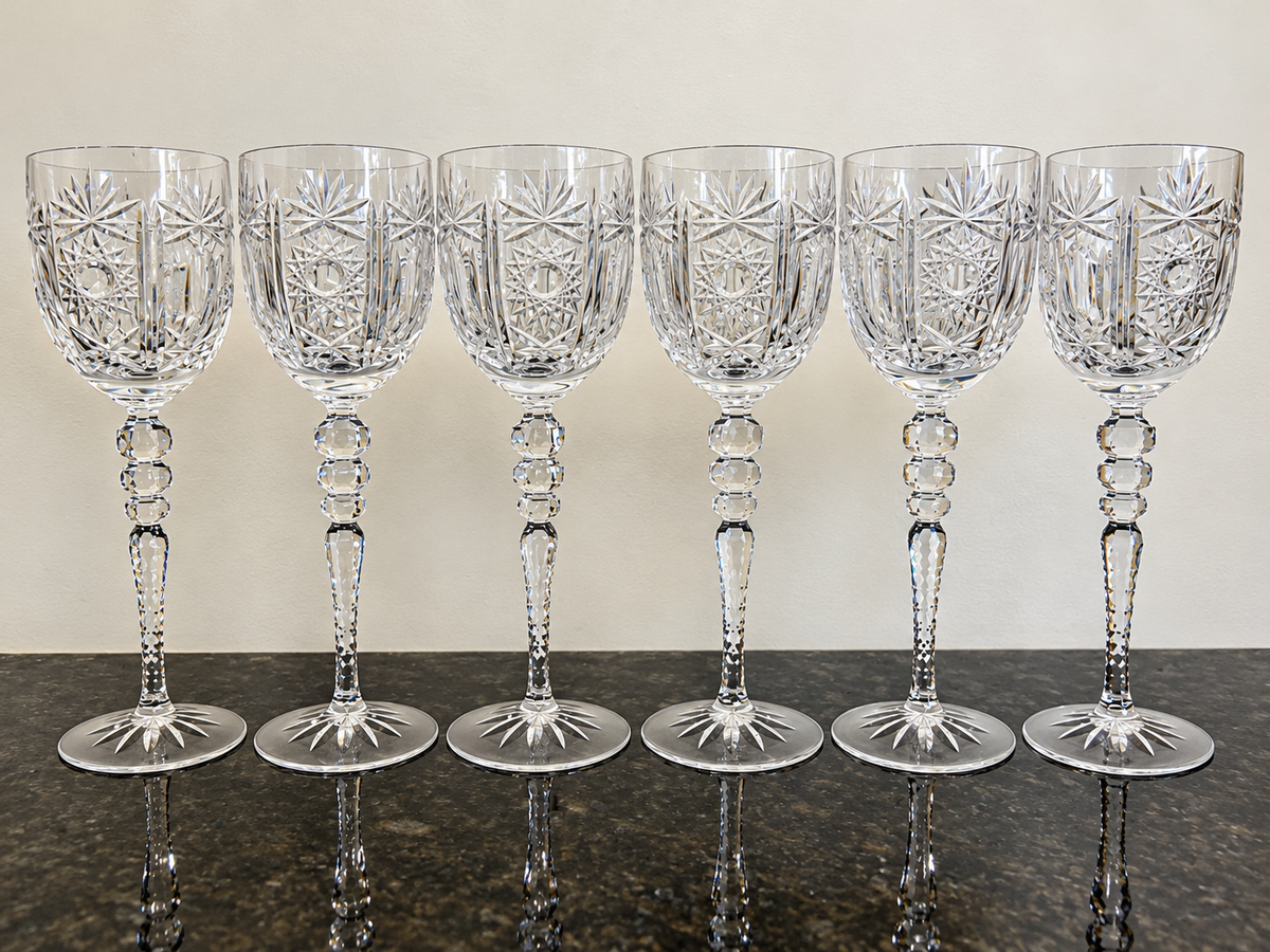 Enhanced full-set photograph of six tall hand-cut crystal hock goblets on dark stone
