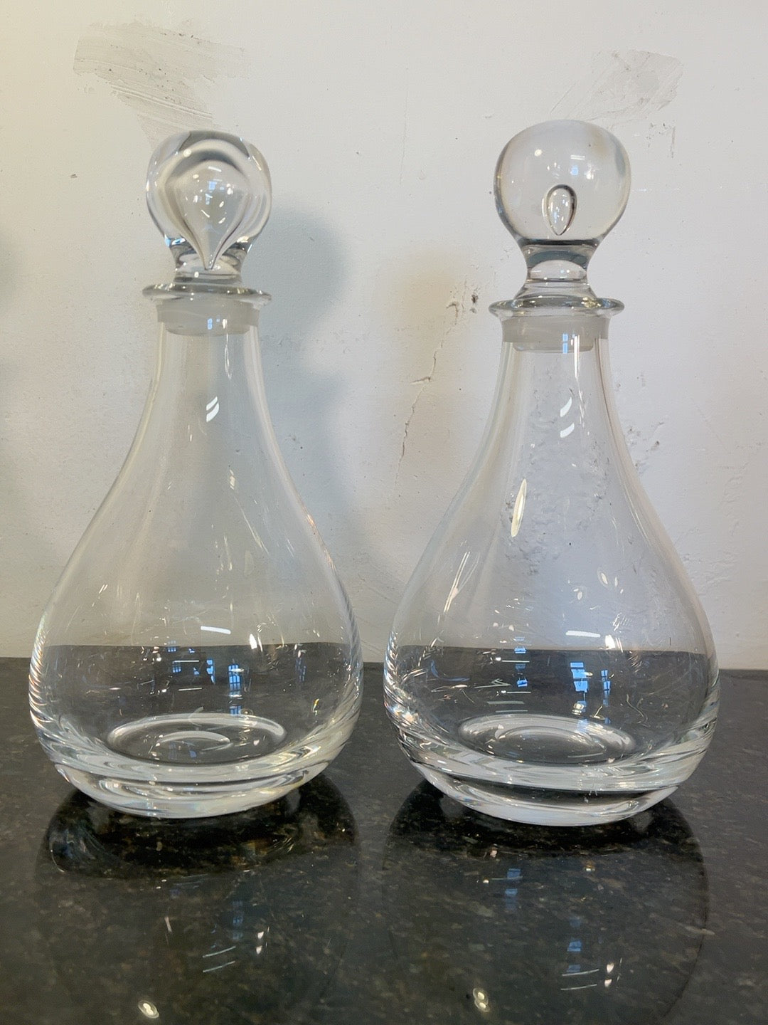 Unedited original product photograph of the exact pair of glass decanters with different stoppers on black stone