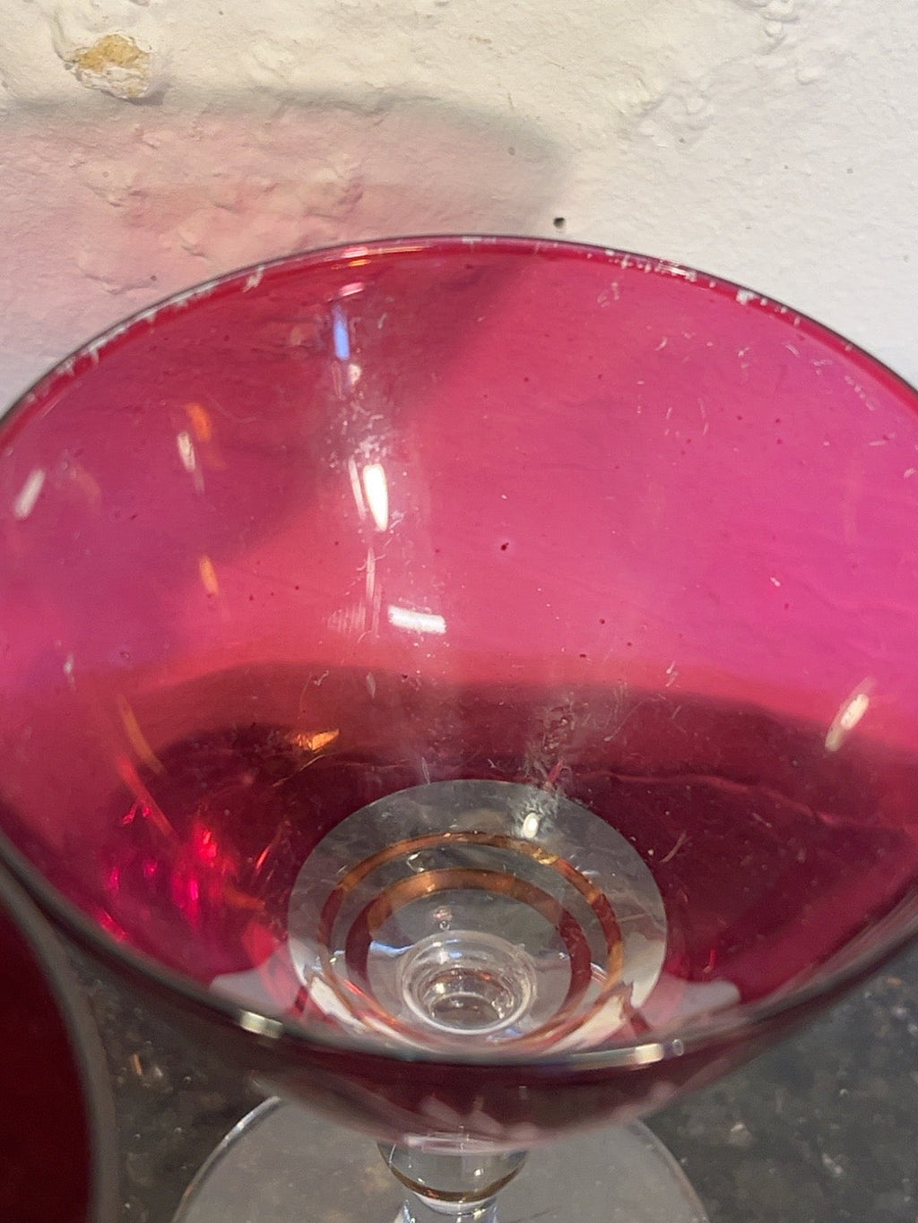 Close-up inside ruby red cocktail glass showing rim wear